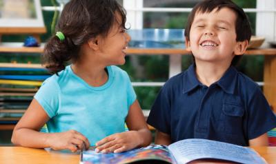 Two children enjoying reading a book.