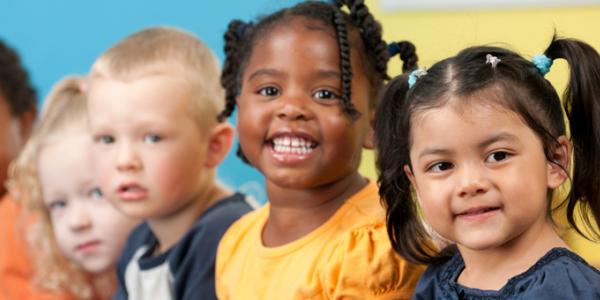 A group of diverse young children standing in a line and smiling