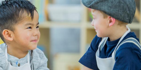 Two young boys smile at each other. 