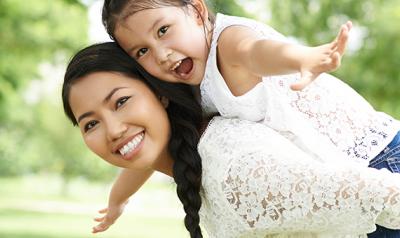 Daughter on her mother's back riding piggyback outside