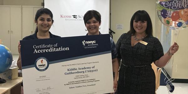 Kiddie Academy staff and NAEYC Accreditation team pose for a picture with accreditation certificate.