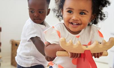 Two toddlers playing on rocking horse