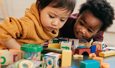 Two toddlers playing with blocks