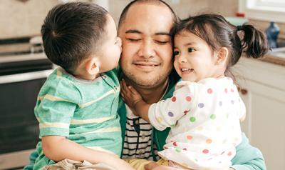 Father hugging toddler son and daughter