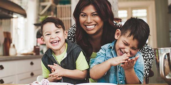 Mother and two sons sitting at the kitchen table and laughing