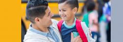 Father and son hugging by the school bus