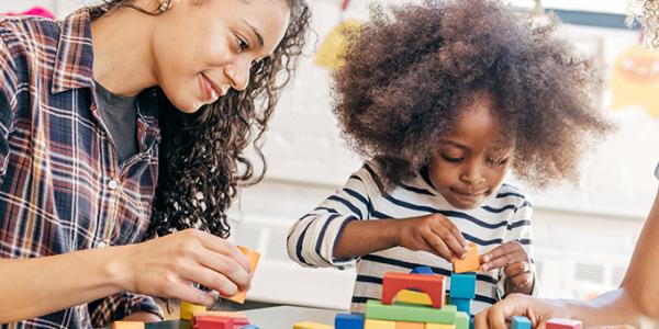 Girl building a structure while her teacher observes