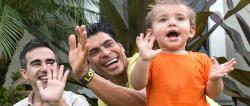 Two happy parents clapping along with their young child.