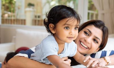 Toddler climbing on table with mother holding her.