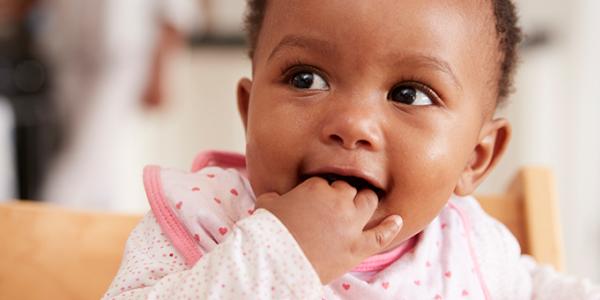 Cute baby smiling with fingers in mouth