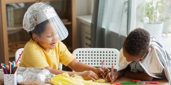 Two children coloring a prop created for dramatic play