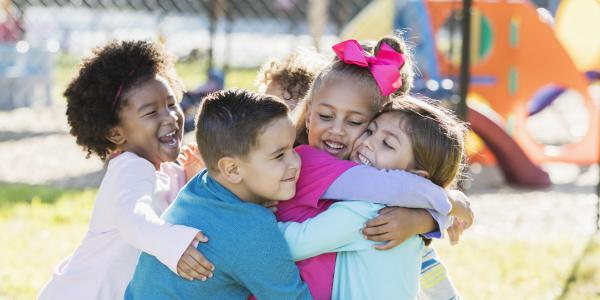 Young children on a playground hugging