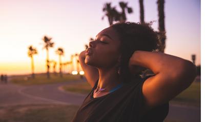 a person closing their eyes at a sunrise beach