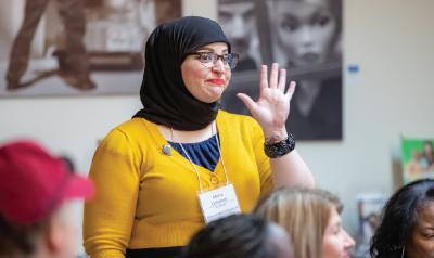 a person raising their hand to speak in a room full of people