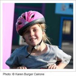 Young girl on a bike wearing a pink helmet