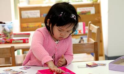 A young child playing with cards on a table.