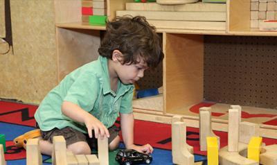 Young child playing on the floor in the block center of a classroom