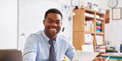 Male teacher in a classroom at a desk