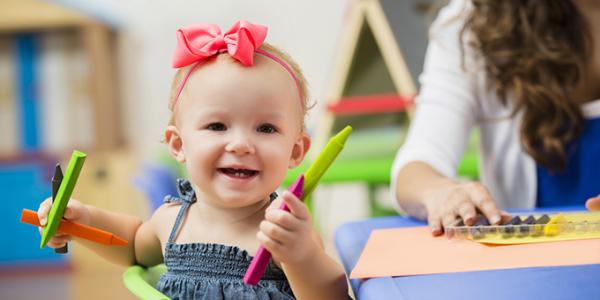 Child holding markers and smiling