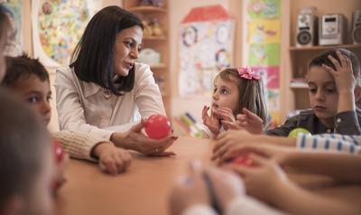 Children and teacher with red ball at table