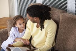 a parent talking to a child on the sofa