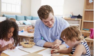 Male teacher in a classroom with two preschool girls