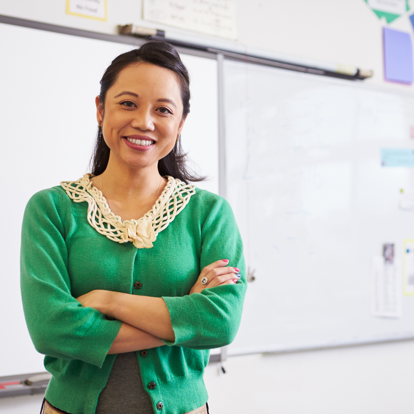 Teacher with arms akimbo smiles.