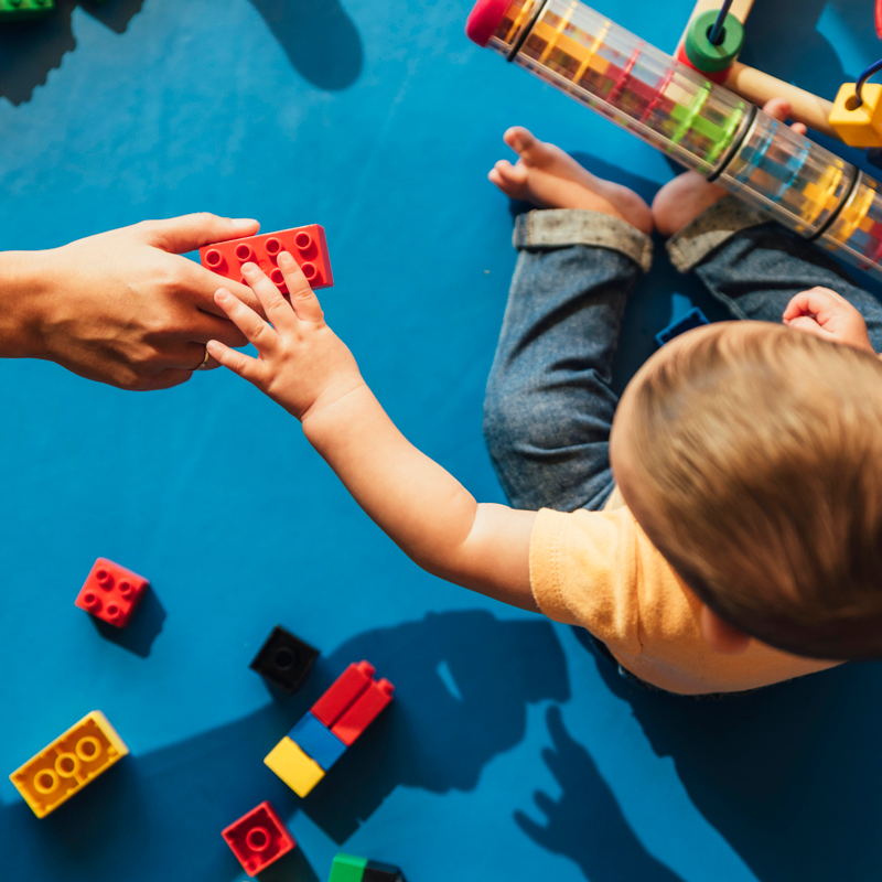 A teacher hands a small child a toy.