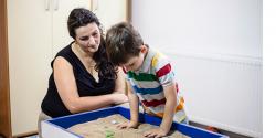  Teacher watching a young boy play in a sandbox