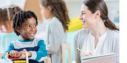 Teacher and preschool boy smiling in a classroom