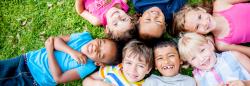 Seven children outside on the grass.