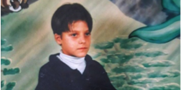 A picture of the author in 3rd grade.  Shows a boy sitting in front of a painted background.