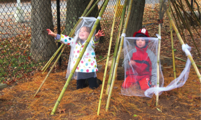 Two children playing outside under  long bamboo poles