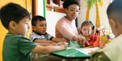 A teacher guides children as they color.