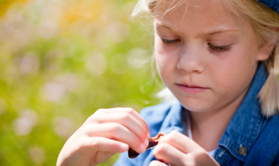 a child wearing a baseball hat holding a worm outside