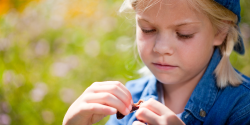 a child wearing a baseball hat holding a worm outside