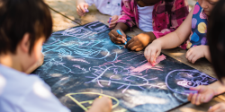 Children drawing with chalk outside.