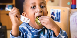 A child eats a piece of broccoli.