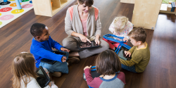 A teacher with a group of children holding tablets.